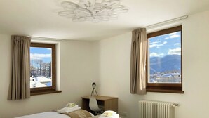 A hotel room with two beds, a desk with a lamp, a radiator, and windows with curtains. - 104 – 6 PAX TERRACE (LAVARONE)