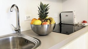 Una cocina con un lavaplatos de acero inoxidable, un frutero en la encimera y un tostador.