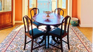 A dining area with a table and chairs, a chandelier, and a view of a mountainous landscape through open doors.