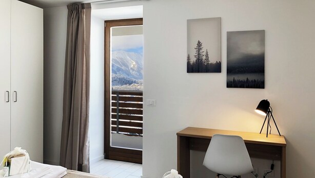 A hotel room with a bed, a desk, a chair, a lamp, and artwork on the wall. - Apartment 2+2 with panoramic terrace (201) (LAVARONE)