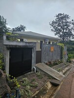 Un edificio moderno con fachada de concreto, puerta de garaje negra y una entrada pequeña con escalones.