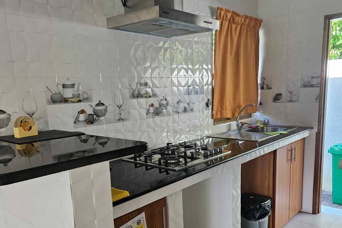 A compact kitchen with a gas stove, sink, and white tiled backsplash.