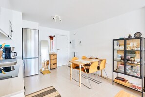 Una cucina moderna con frigorifero in acciaio inossidabile, un'area pranzo con tavolo e sedie in legno e una vetrina con stoviglie.