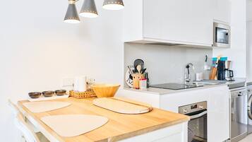 A modern kitchen with white cabinets, a wooden countertop, a microwave, a sink, and a stove.