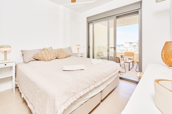 A bedroom with a bed, a nightstand, a lamp, a sliding glass door to a balcony, and a view of the city. - Apartment 'Marinsa Beach Torrox' with Sea View, Wi-Fi and Air Conditioning (Málaga)