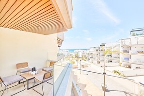 A balcony with a wooden ceiling, a table with chairs, and a view of a coastal residential area. - Apartment 'Marinsa Beach Torrox' with Sea View, Wi-Fi and Air Conditioning (Málaga)