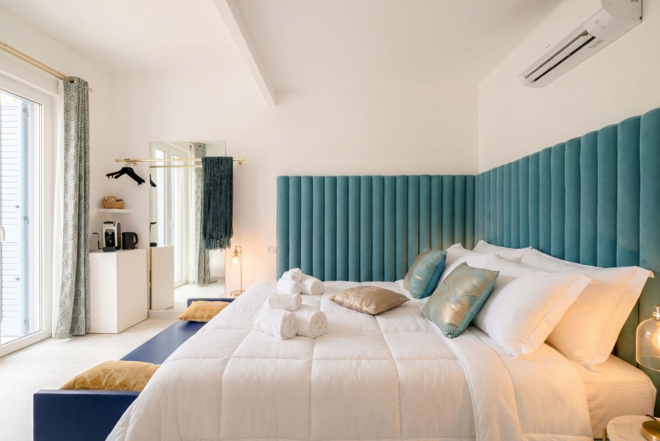 Ein modernes Hotelzimmer mit einem großen Bett, einem Nachttisch, einem Spiegel und einem Fenster mit Vorhängen.
