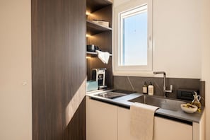 Eine kleine Küche mit integriertem Backofen, Spüle und Fenster über der Arbeitsplatte.