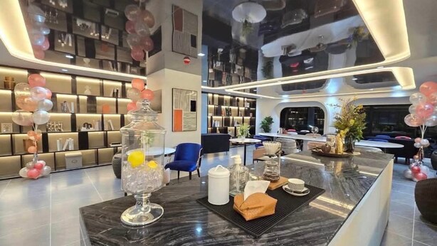 Eine moderne Hotelhalle mit einem Marmor-Rezeptionstresen, einer Bücherwand und einer Sitzecke.