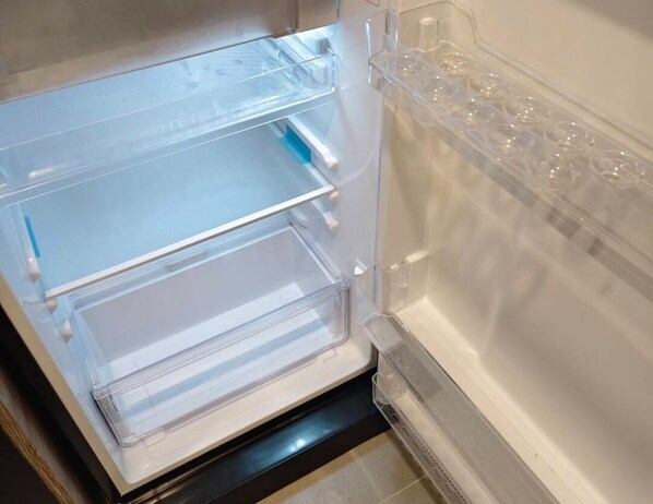 An open refrigerator with clear plastic shelves and a water dispenser. - Cybiq Ratchada 32, Bangkok by Pikul (Krung Thep Maha Nakhon)
