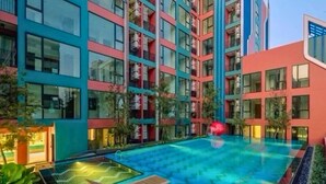 Ein modernes Gebäude mit Poolbereich auf dem Dach, einschließlich Liegestühlen und einem gut beleuchteten Schwimmbecken.