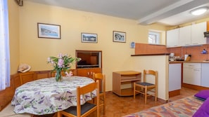 Un espacio habitable compacto con comedor, kitchenette y televisor.