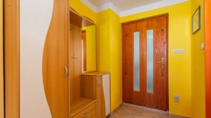 Una habitación con un armario de madera, una puerta con paneles de vidrio esmerilado y suelo de baldosas.