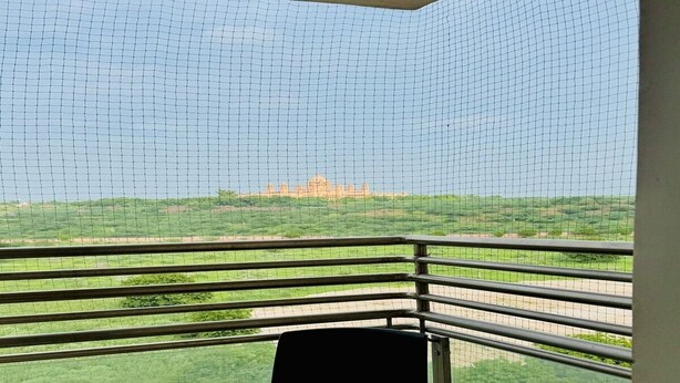 A balcony with a view of a large, historic building in the distance. - Hotel Raj Villa (Jodhpur)