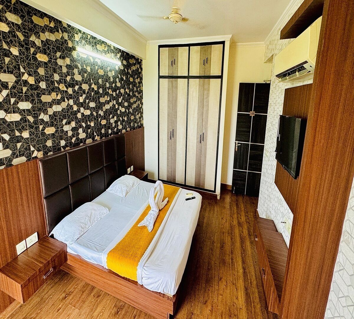 A hotel room with a bed, a wardrobe, a television, and a patterned wall.
