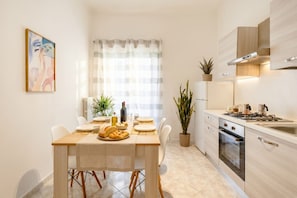 Una cocina moderna con una mesa de comedor, sillas, estufa, horno y plantas en macetas.