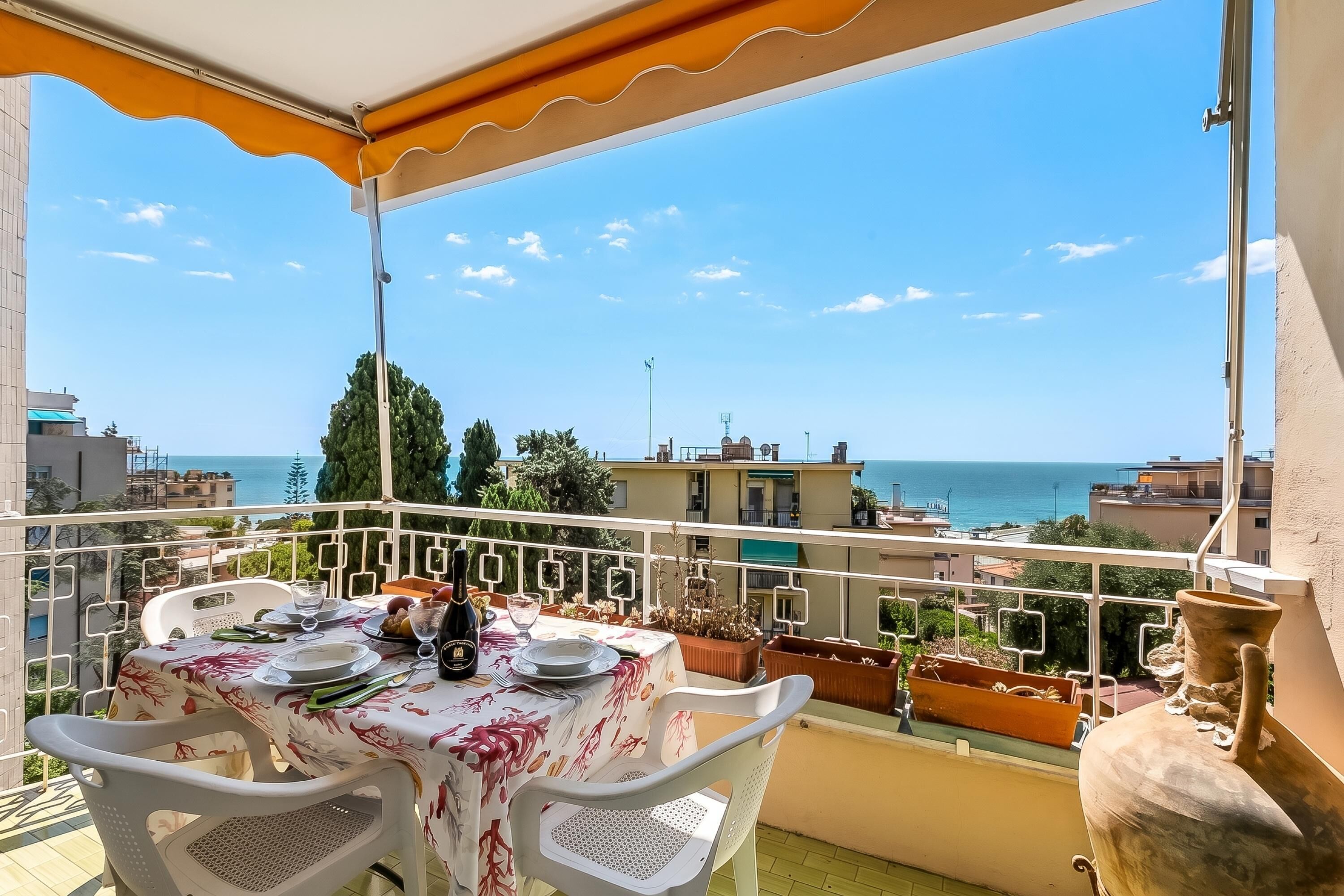 Un balcon avec une table dressée pour deux personnes, offrant une vue sur la côte.