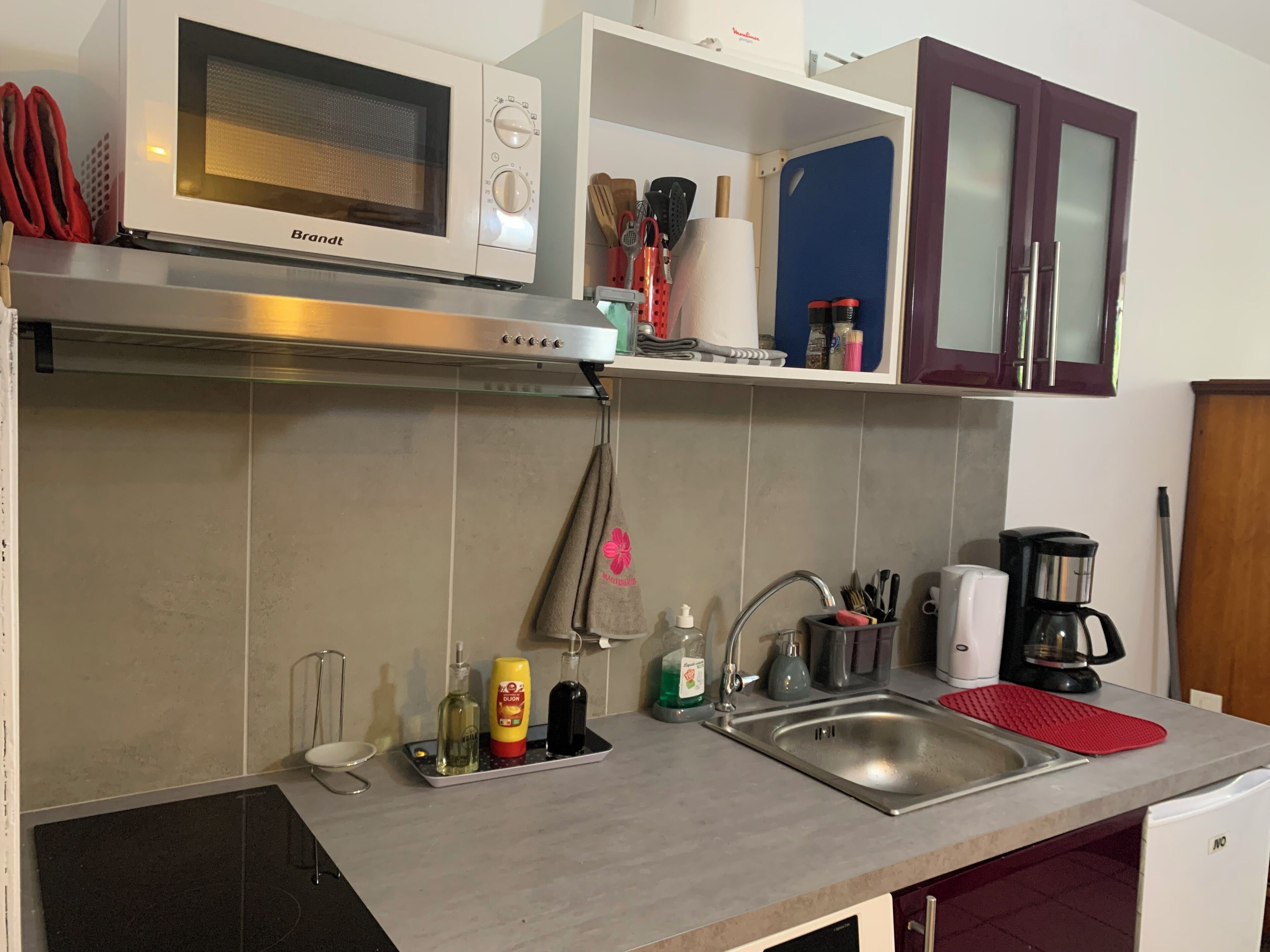 A kitchen with a built-in microwave, stainless steel sink, and a coffee maker.