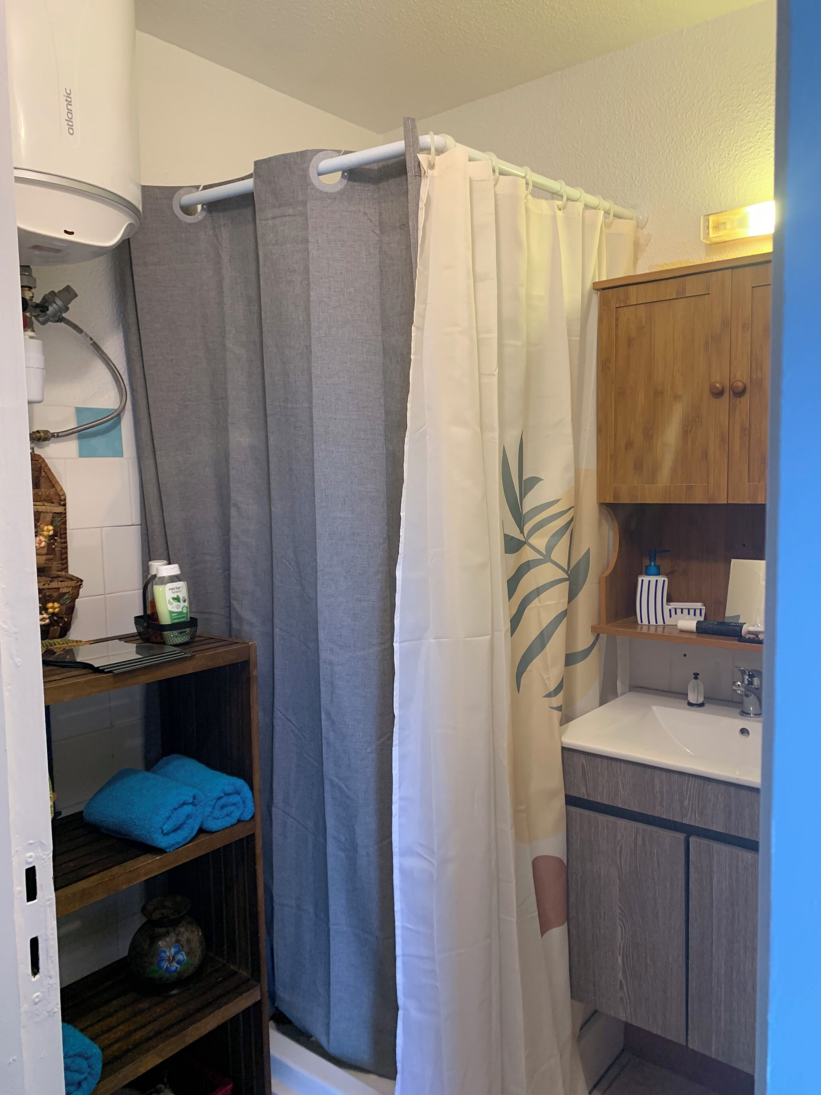 Un baño con cortina de ducha, un lavabo y un armario de madera.