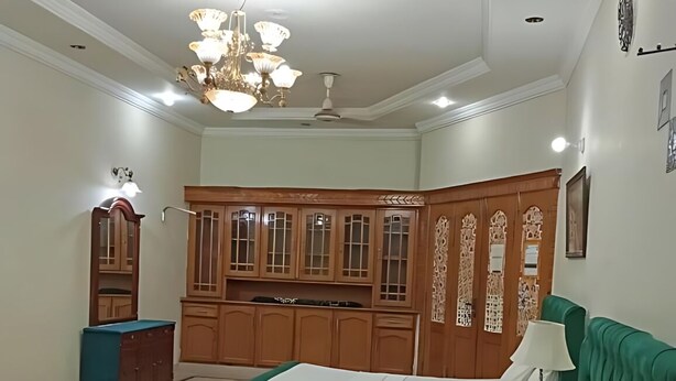 Una camera d'albergo con due letti, un armadietto in legno, un lampadario e una ventola a soffitto.