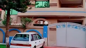 Un edificio di due piani con un'auto bianca parcheggiata davanti.