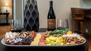 A charcuterie board with various meats, cheeses, and fruits, a wine bottle, and glasses on a table. - Rosé  All Day Hideaway (Walla Walla)