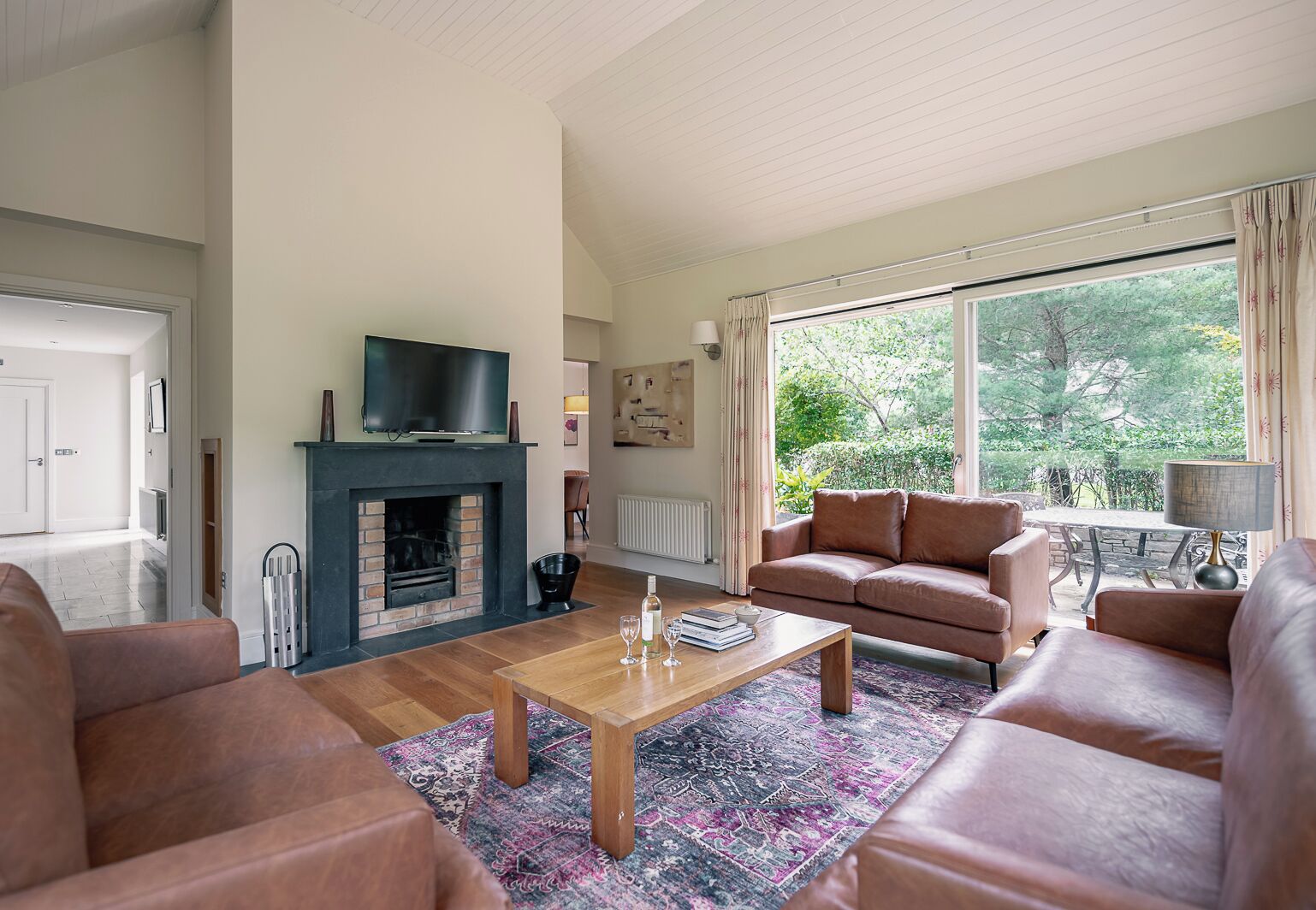 A living room with a fireplace, leather sofas, a coffee table, and a television.