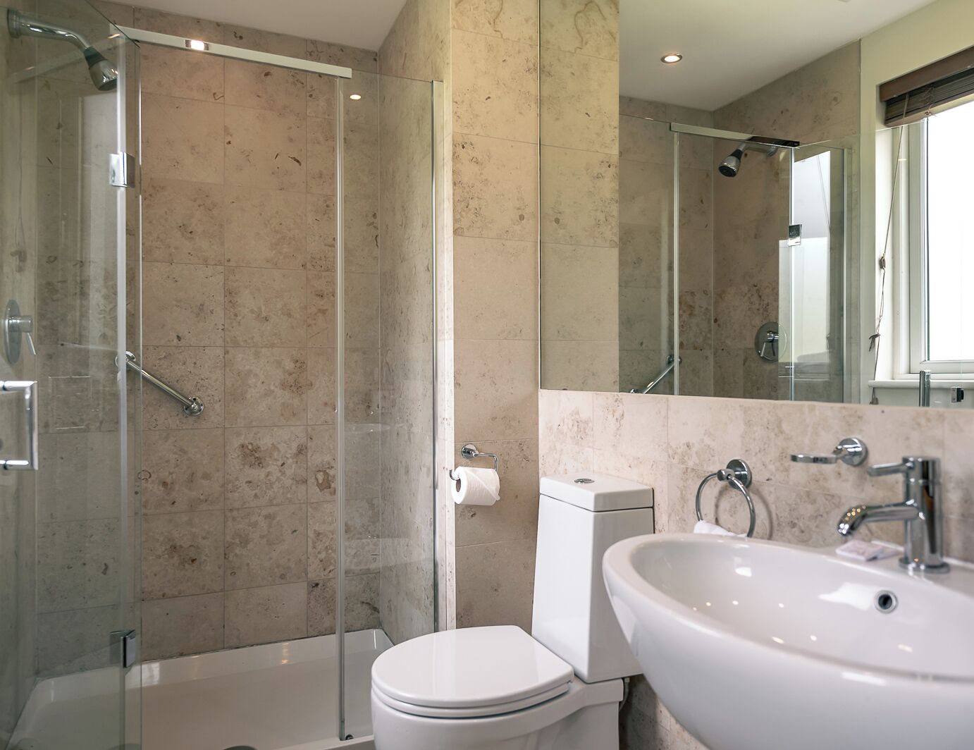 A modern bathroom with a glass-enclosed shower, a white toilet, and a large sink.