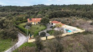 A house with a swimming pool, surrounded by a lush green landscape.