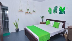 A bedroom with a bed, green pillows, a green bedspread, a potted plant, and wall art. - Tranquil 3-bedroom villa in elewankuluma Puttalam , near wilpattu safari park (puttalam)
