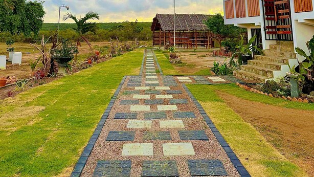 A pathway leading to a building with a thatched roof and a covered porch. - Tranquil 3-bedroom villa in elewankuluma Puttalam , near wilpattu safari park (puttalam)