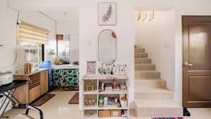 A kitchen with a countertop, a sink, a mirror, and a staircase leading to a door. - Charming Iloilo City House With Garden View (Iloilo)
