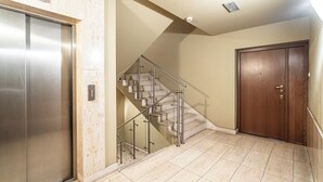 Een net, modern interieur met een metalen lift, een glazen trap en een houten deur.