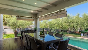 An outdoor dining area with a glass table and wicker chairs, overlooking a swimming pool and lush greenery. - Villa Dila by Villas Guide (Medulin)