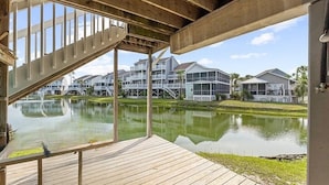 Een houten terras met uitzicht op een meer en huizen op de achtergrond.