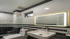 A modern bathroom with a glass-enclosed shower, a white sink, and a large mirror with a yellow frame. - Dancentre Airport Stays - Vyvy Hotel (Ho Chi Minh City)