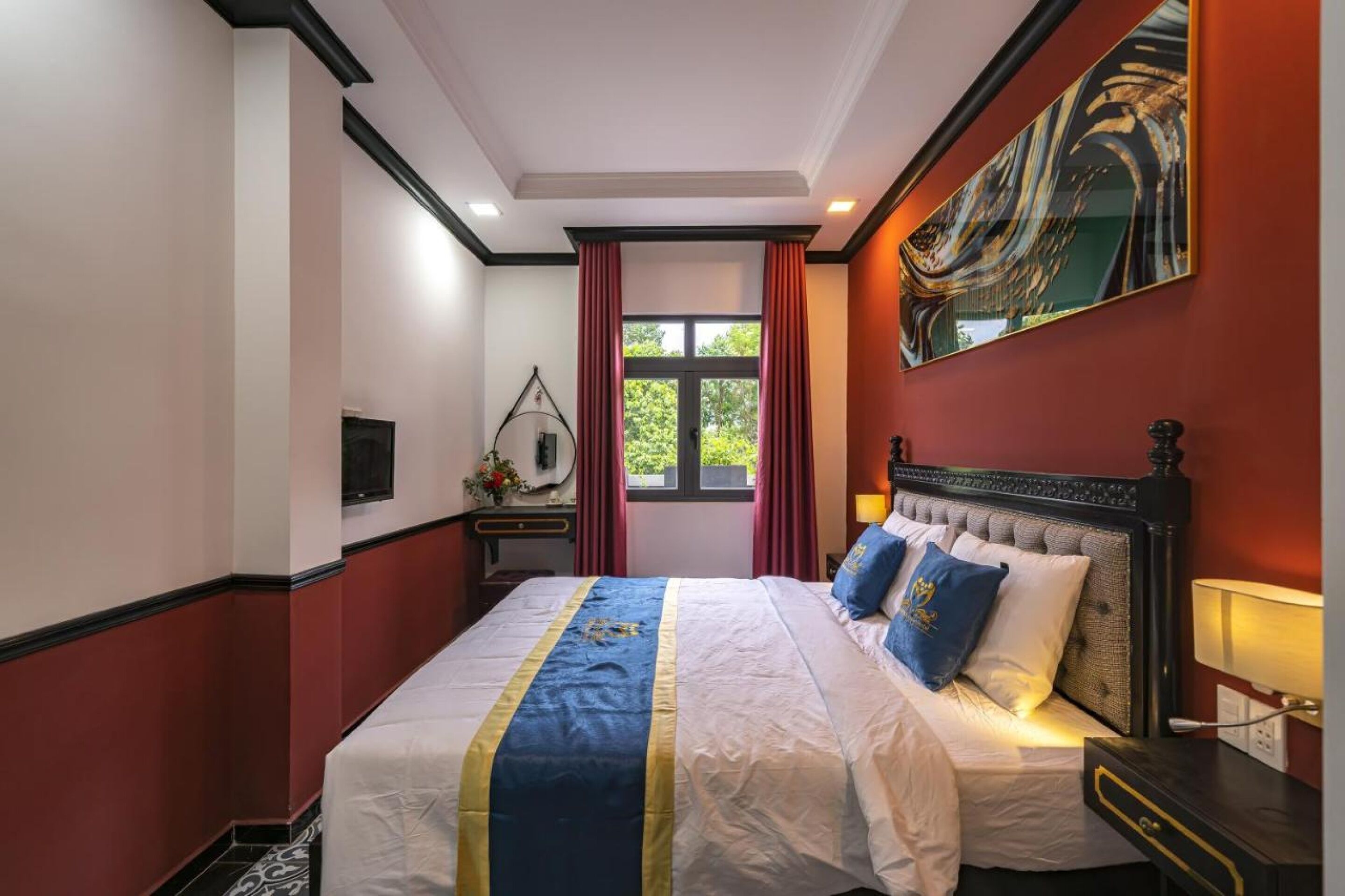 A hotel room with a large bed, a nightstand, a mirror, and a window with curtains.