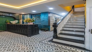 A reception area with a patterned floor, a staircase, and a reception desk. - Dancentre Airport Stays - Vyvy Hotel (Ho Chi Minh City)
