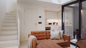 Un interior moderno con un sofá, una mesa de comedor y una escalera que conduce a un nivel superior.