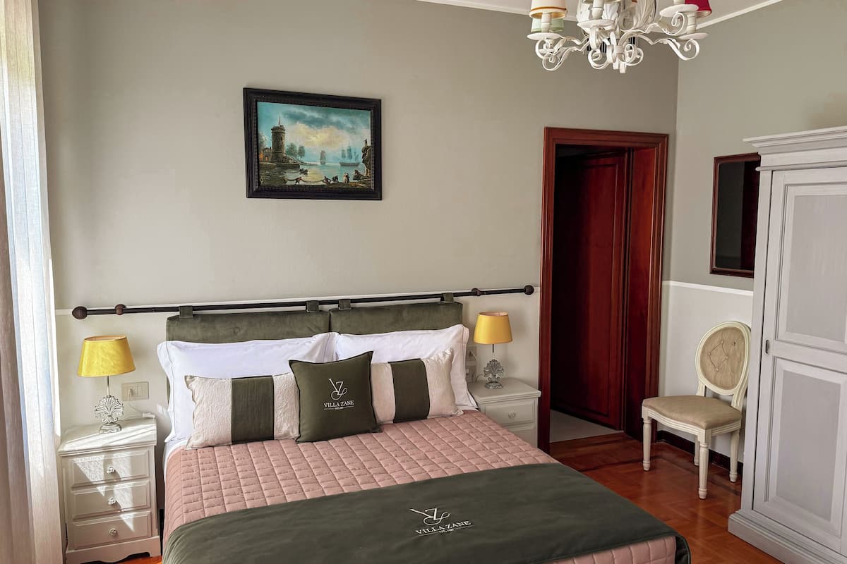 A neatly arranged bedroom with a bed, bedside lamps, a nightstand, a chair, and a wardrobe.