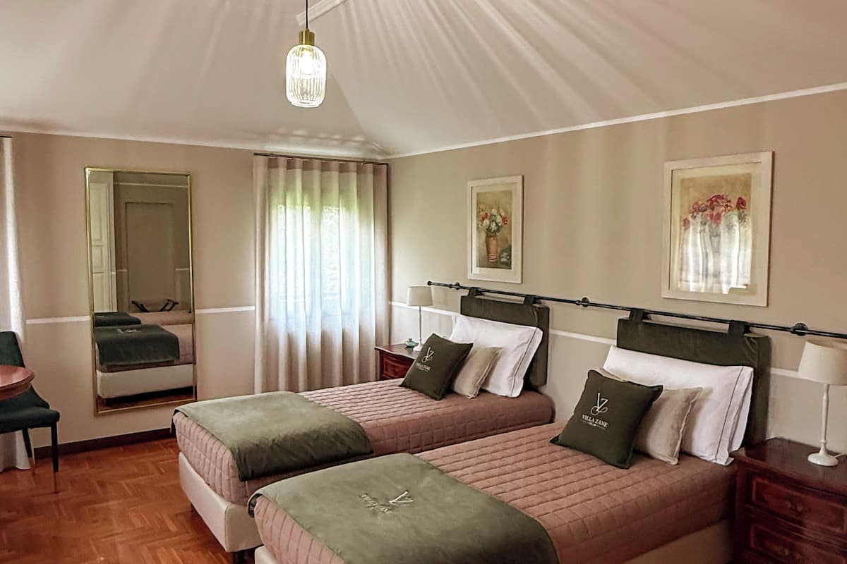 A hotel room with two beds, a mirror, a desk, and a chair.