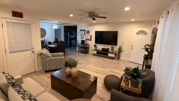 A living room with a sofa, a coffee table, a TV, and a ceiling fan.