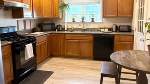 A kitchen with wooden cabinets, a stove, a microwave, and a sink.