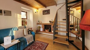 A cozy living room with a blue sofa, a fireplace, and a wooden staircase. - Tatiana - Historic House (Bari)