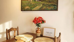 A dining table with a rustic wooden chair, a woven placemat, a vase with red flowers, and a framed sign. - Tatiana - Historic House (Bari)