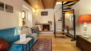 A cozy living room with a blue sofa, a fireplace, a staircase, and a wooden ceiling. - Tatiana - Historic House (Bari)