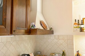 A kitchen with wooden cabinets, a tiled backsplash, and various kitchen items including a kettle, jars, and bottles.