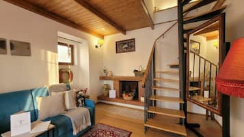 Ein gemütliches Wohnzimmer mit einem blauen Sofa, einem Kamin und einer Holztreppe.