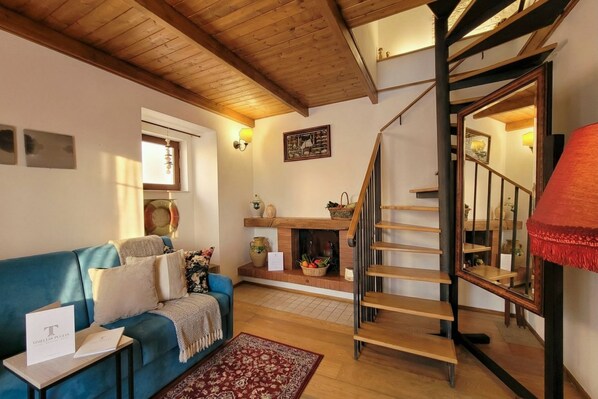A cozy living room with a blue sofa, a fireplace, and a wooden staircase.