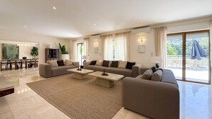 Un salon spacieux comprenant un grand canapé, une table basse et un coin repas avec une table et des chaises.